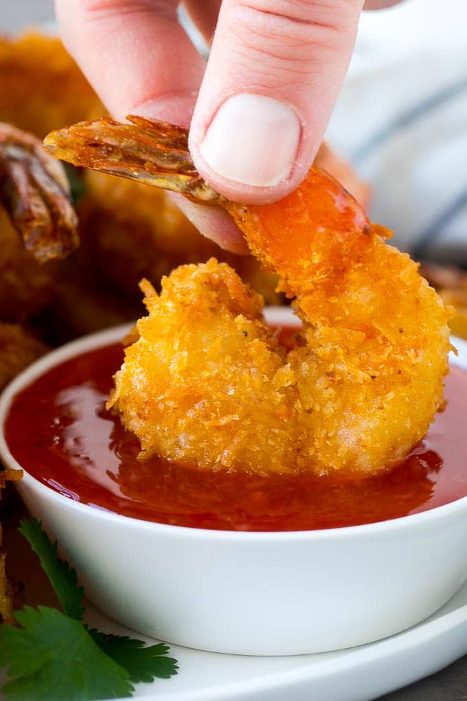 Coconut Shrimp Recipe | Fried Shrimp | Shrimp Appetizer #shrimp #coconut #appetizer #seafood #dinner #ezlod A hand dipping a crispy prawn into a bowl of sweet chili sauce.