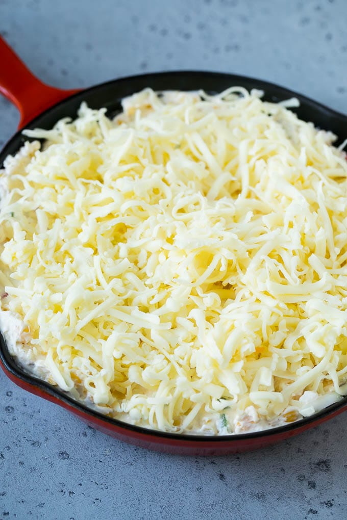 Corn Dip Recipe | Hot Cheese Dip | Bacon Dip #corn #dip #bacon #cheese #appetizer #snack #ezlod A skillet of corn dip covered with shredded cheese.