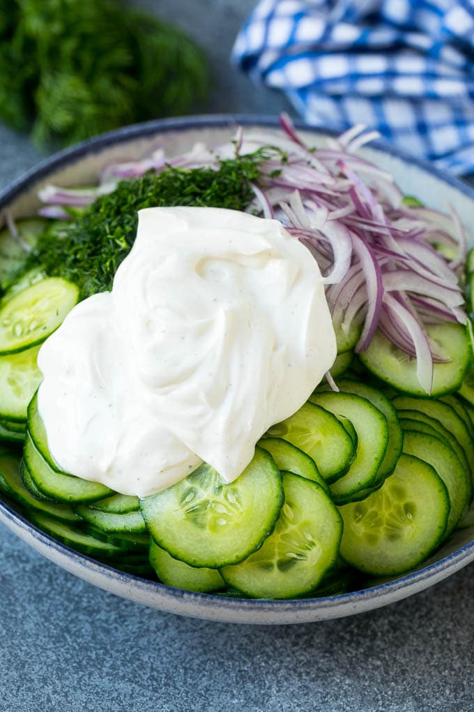 Creamy Cucumber Salad Recipe | German Cucumber Salad | Cucumber Salad #cucumber #salad #dinner #lunch #ezlod #cucumbersalad Cucumbers, red onion and dill in a bowl topped with creamy dressing.