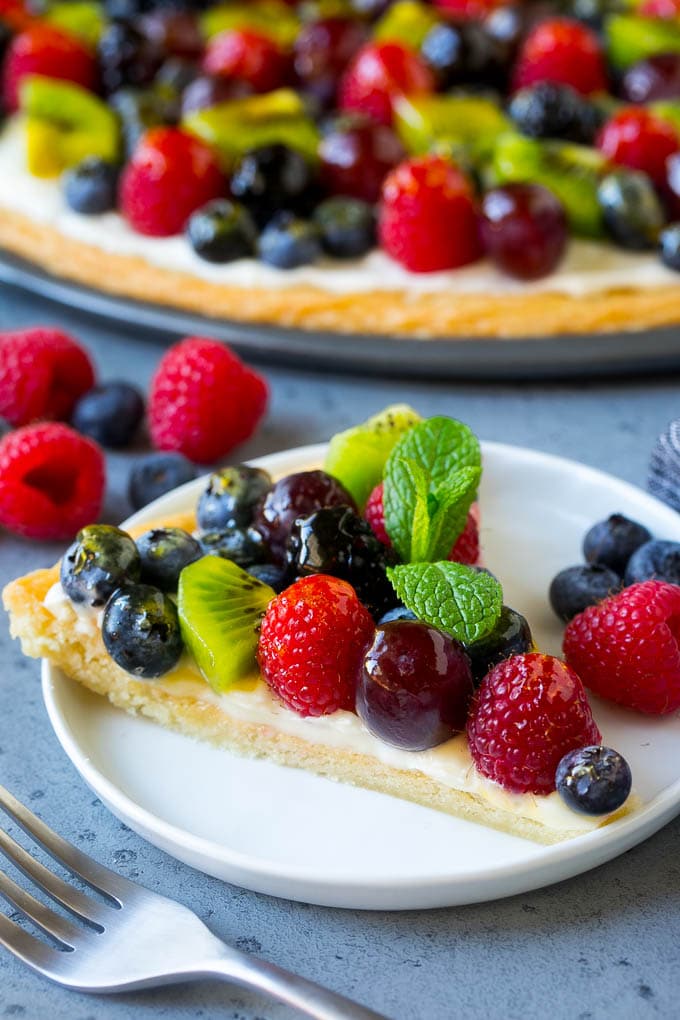 Fruit Pizza Recipe | Dessert Pizza | Fruit Dessert #cookie #fruit #pizza #dessert #sweets #ezlod A slice of fruit pizza topped with cream cheese frosting and berries.