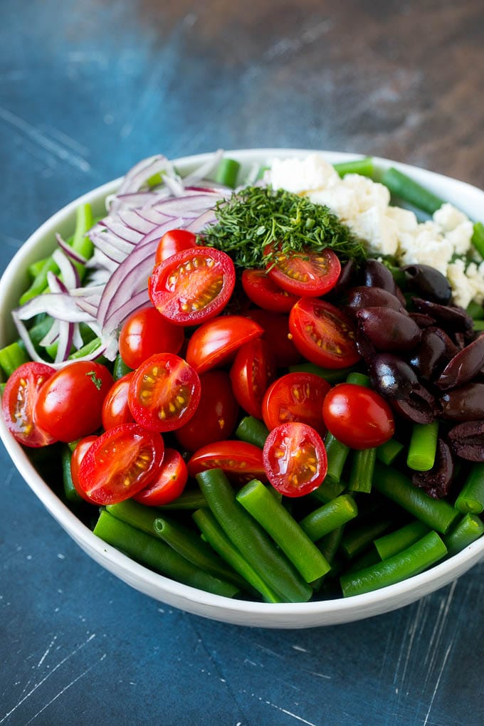 Green Bean Salad Recipe | String Bean Salad | Chopped Salad #greenbeans #tomatoes #olives #salad #cleaneating #lowcarb #glutenfree #ezlod Vegetables like cherry tomatoes, red onion and olives in a bowl with feta cheese.