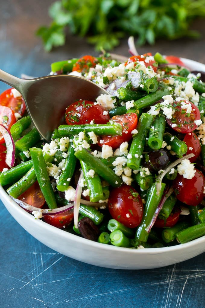 Green Bean Salad Recipe | String Bean Salad | Chopped Salad #greenbeans #tomatoes #olives #salad #cleaneating #lowcarb #glutenfree #ezlod A serving spoon in a bowl of green bean salad.