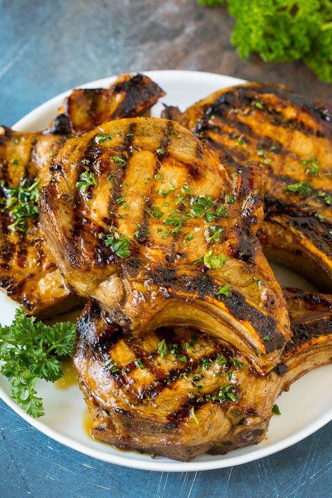 Pork Chop Marinade Recipe | Marinated Pork Chops | Grilled Pork Chops #pork #porkchops #grilling #dinner #ezlod Pork chop marinade on grilled pork chops. The pork chops are on a serving plate garnished with parsley.