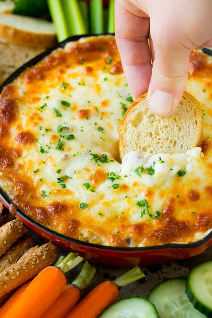 Reuben Dip Recipe | Corned Beef Dip | Cheese Dip #dip #cheese #cornedbeef #appetizer #lowcarb #keto #ezlod A hand scooping out a serving of Reuben dip with baguette.