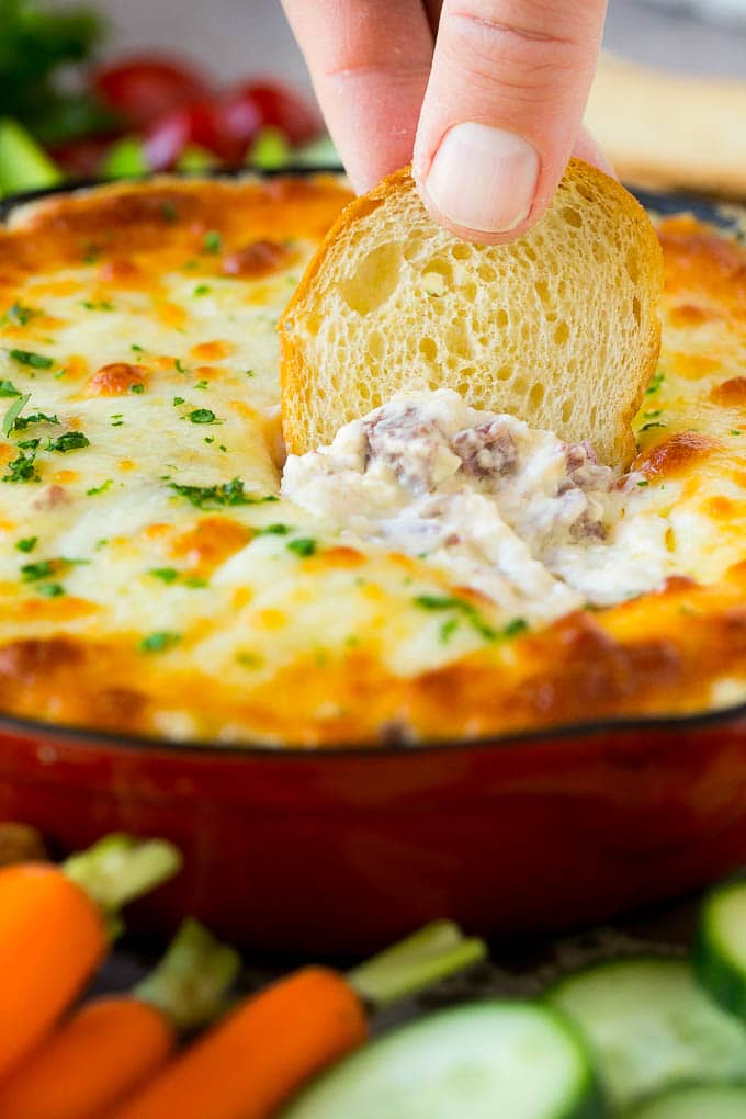 Reuben Dip Recipe | Corned Beef Dip | Cheese Dip #dip #cheese #cornedbeef #appetizer #lowcarb #keto #ezlod A baguette chip dipping into a skillet of Reuben dip.
