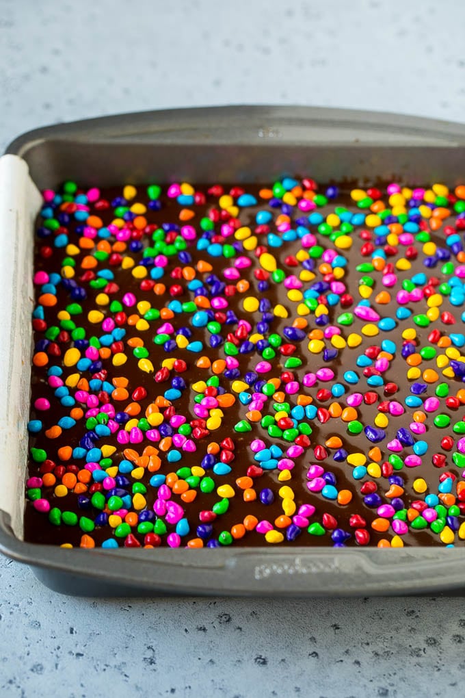 Cosmic Brownies Recipe | Cocoa Brownies | Frosted Brownies #brownies #chocolate #dessert #ezlod #sprinkles A pan of cosmic brownies with rainbow sprinkles on top.