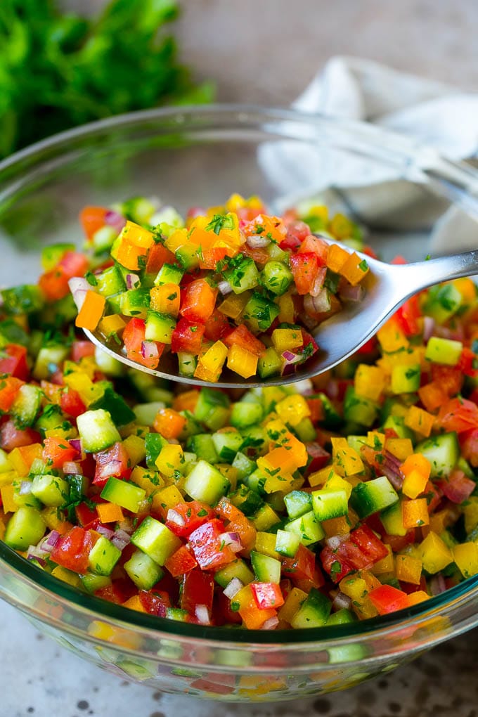 Israeli Salad Recipe | Cucumber Salad | Tomato Salad | Chopped Salad #salad #cleaneating #healthy #glutenfree #lowcarb #keto #sidedish #lunch #ezlod A spoon holding up a serving of Israeli salad.