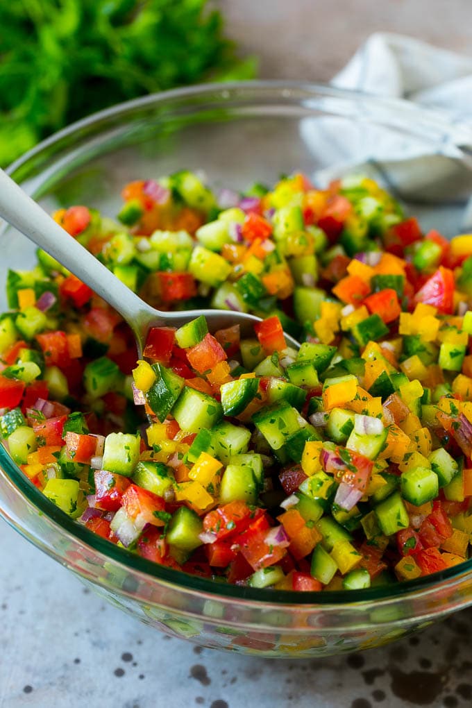 Israeli Salad Recipe | Cucumber Salad | Tomato Salad | Chopped Salad #salad #cleaneating #healthy #glutenfree #lowcarb #keto #sidedish #lunch #ezlod A bowl of Israeli salad with a serving spoon in it.