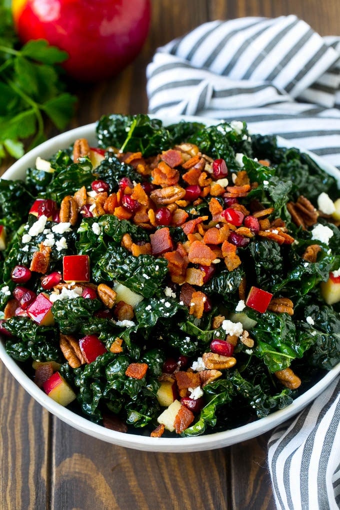 Apple Kale Salad Recipe | Kale Recipe | Fall Salad #kale #apples #bacon #salad #feta #dinner #lunch #ezlod A bowl of tuscan kale salad garnished with cooked bacon.