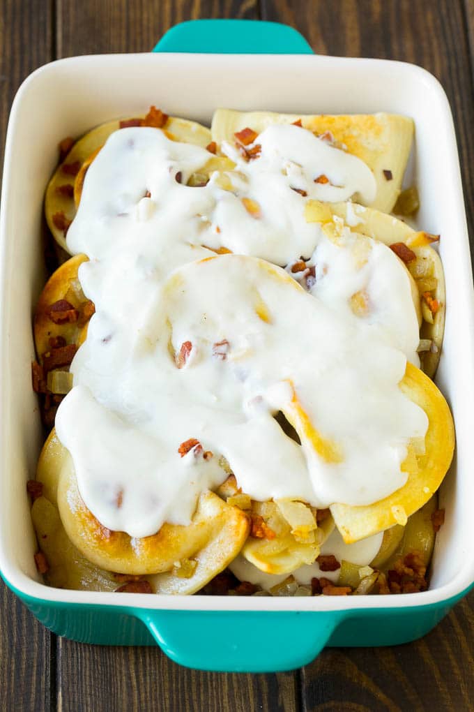 Pierogi Casserole Recipe | Potato Casserole #pierogis #casserole #bacon #cheddar #dinner #ezlod Dumplings in a baking dish covered with creamy sauce.