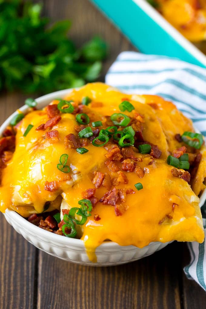 Pierogi Casserole Recipe | Potato Casserole #pierogis #casserole #bacon #cheddar #dinner #ezlod A bowl of pierogi casserole topped with cheddar cheese and bacon.