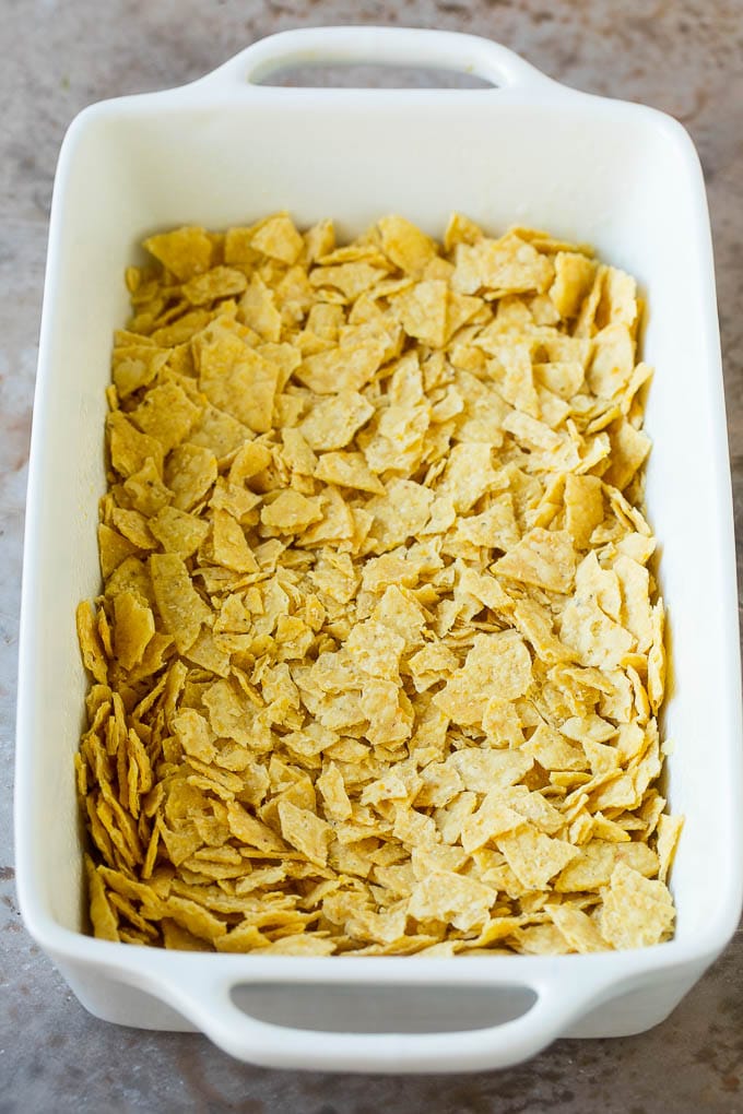 Taco Casserole Recipe | Mexican Casserole | Beef Casserole #casserole #tacos #beef #dinner #cheese #ezlod Crushed tortilla chips in a casserole dish.