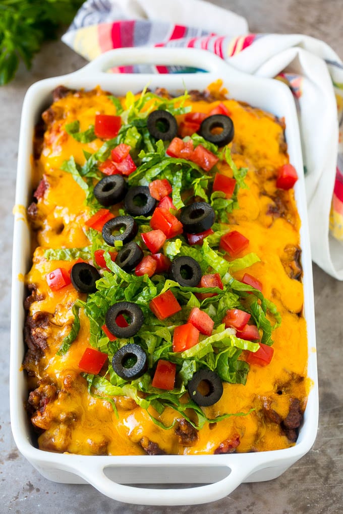 Taco Casserole Recipe | Mexican Casserole | Beef Casserole #casserole #tacos #beef #dinner #cheese #ezlod Taco casserole in a baking dish topped with melted cheese, lettuce, tomato and olives.