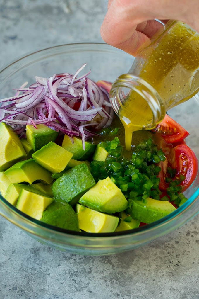 Tomato Avocado Salad Recipe | Avocado Salad | Tomato Salad #salad #tomato #avocado #glutenfree #cleaneating #dinner #ezlod #healthy Dressing being poured over chopped veggies.