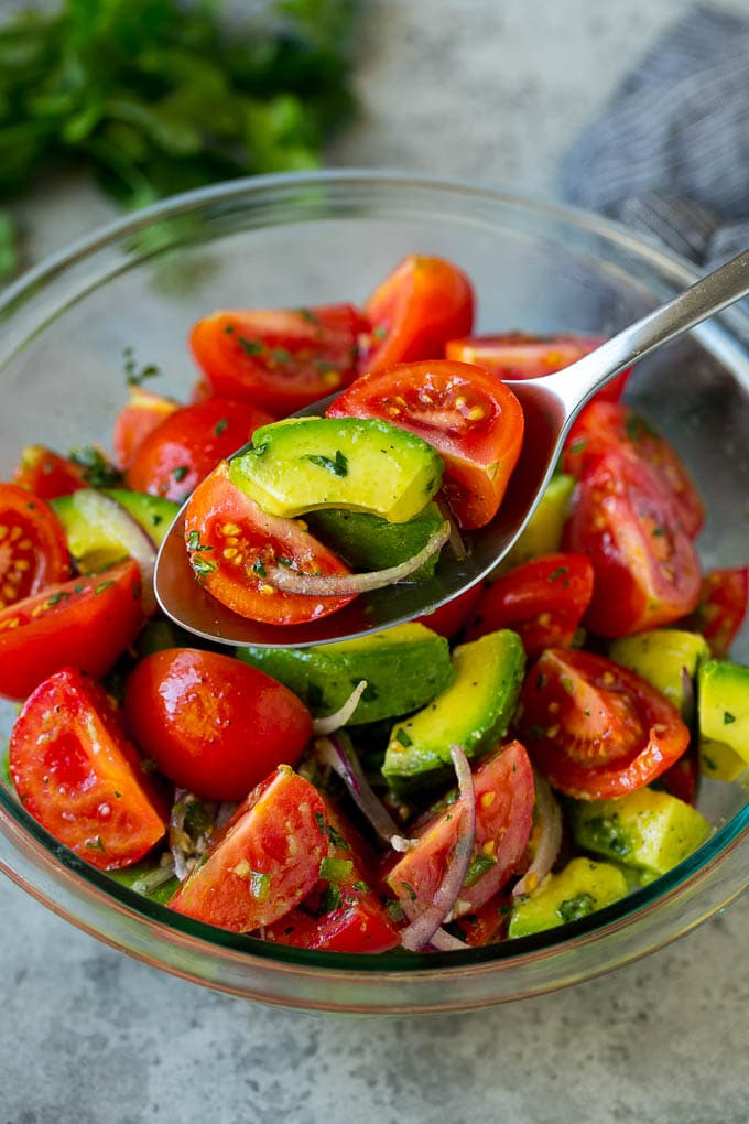 Tomato Avocado Salad Recipe | Avocado Salad | Tomato Salad #salad #tomato #avocado #glutenfree #cleaneating #dinner #ezlod #healthy A serving spoon of veggies in a lime dressing.