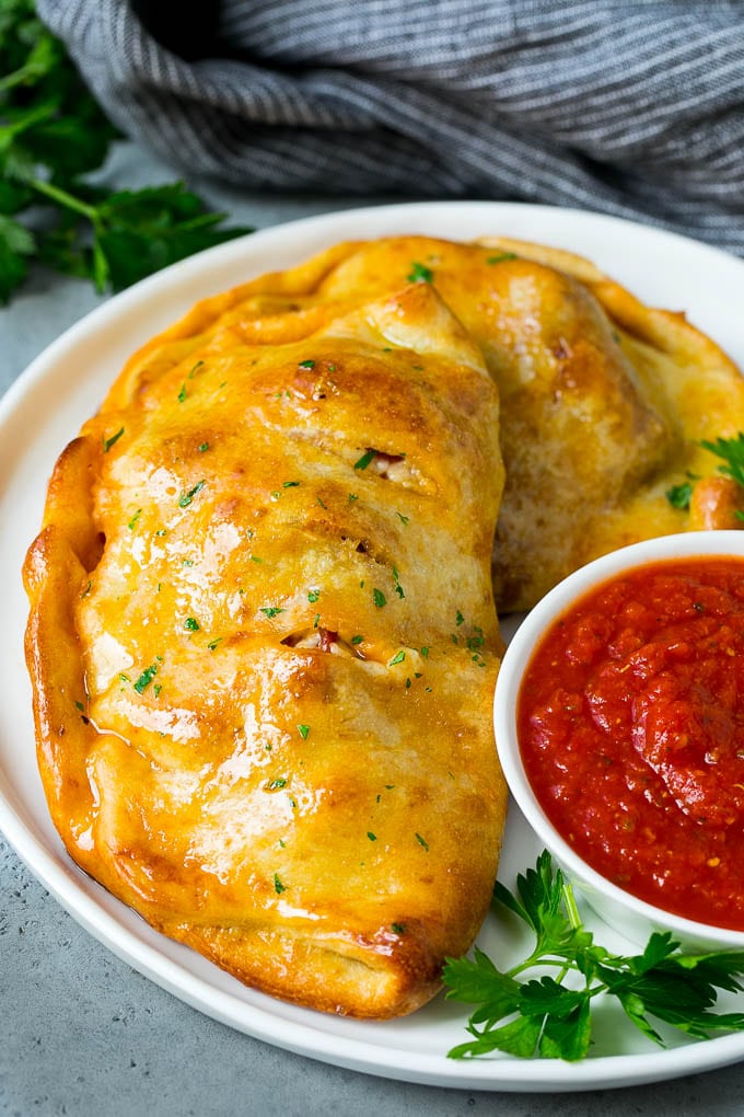 Calzone Recipe | Pizza Pockets #pizza #calzone #pepperoni #sausage #peppers #dinner #ezlod #cheese A homemade calzone served with pizza sauce.