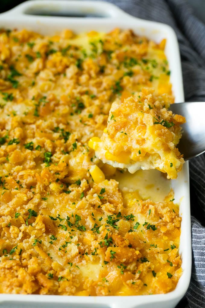 Scalloped Corn | Corn Casserole #corn #casserole #cheese #sidedish #dinner #ezlod A serving spoon lifting out a portion of scalloped corn.