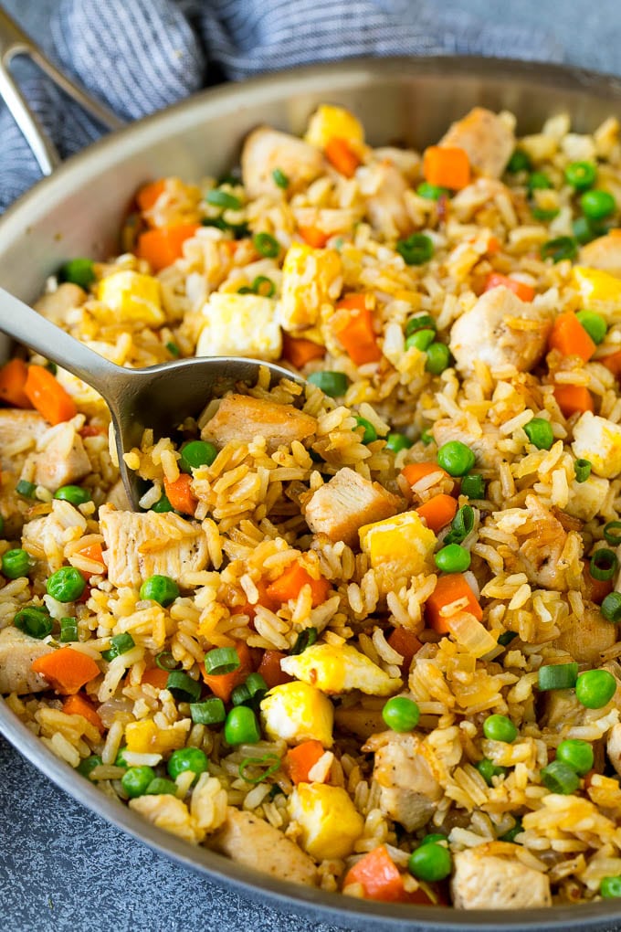 Chicken Fried Rice Recipe | Chinese Fried Rice #rice #chicken #peas #carrots #sidedish #dinner #ezlod A serving spoon in a pan of chicken fried rice.