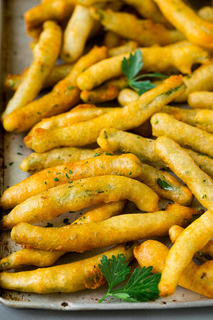 Fried Green Beans Recipe | Green Beans #greenbeans #appetizer #snack #ezlod A sheet pan of fried green beans garnished with chopped parsley.