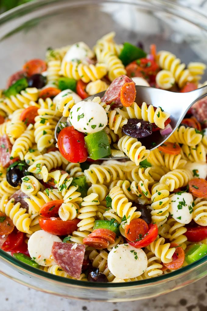 Italian Pasta Salad | Pasta Salad Recipe #pasta #salad #pastasalad #pepperoni #salami #olives #cheese #sidedish #ezlod A serving spoon in a bowl of Italian style pasta salad.