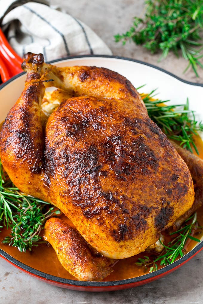 Rotisserie Chicken Recipe | Roasted Chicken #chicken #dinner #ezlod #comfortfood A rotisserie chicken in a red skillet with sprigs of fresh herbs.