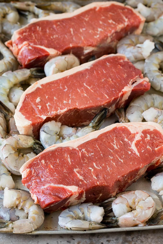 Surf and Turf Recipe | Seared Steak #steak #shrimp #keto #lowcarb #dinner #ezlod Raw steaks and shrimp on a sheet pan.
