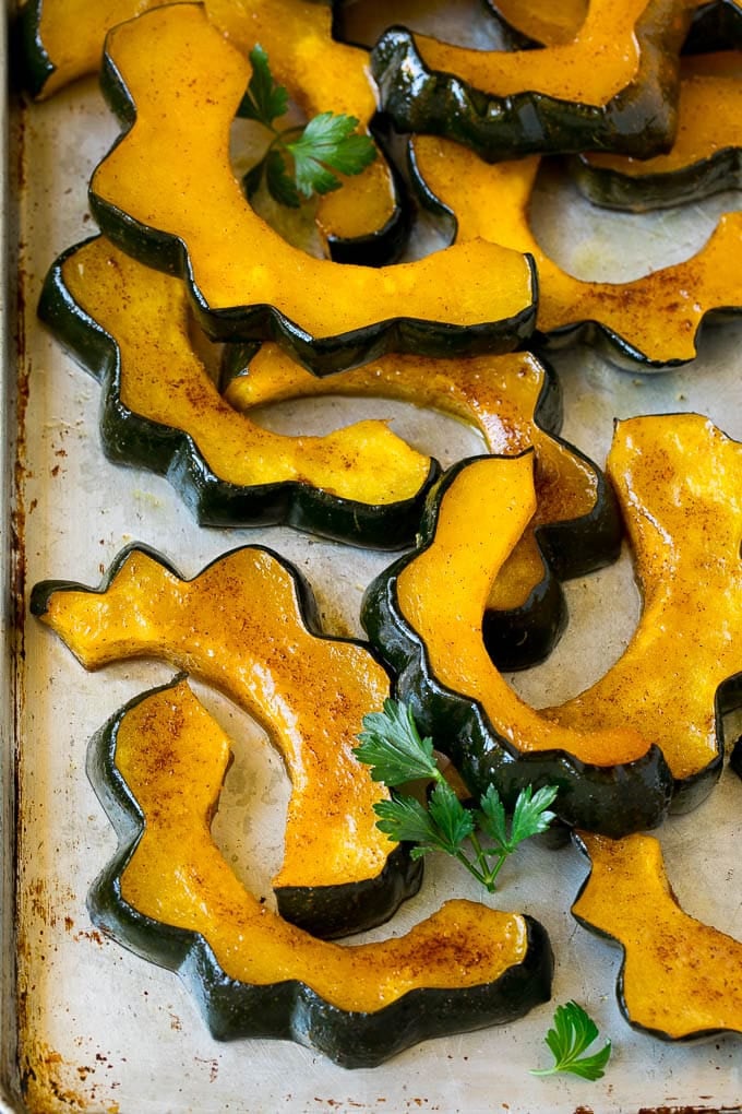 Roasted Acorn Squash | Acorn Squash Recipe #squash #winter #sidedish #dinner #ezlod Sliced of cinnamon roasted acorn squash on a sheet pan.