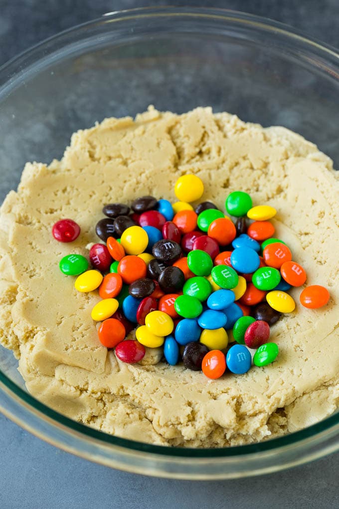 M&M Cookies Recipe #cookies #chocolate #baking #dessert #sweets #ezlod A bowl of cookie dough with chocolate candies in it.