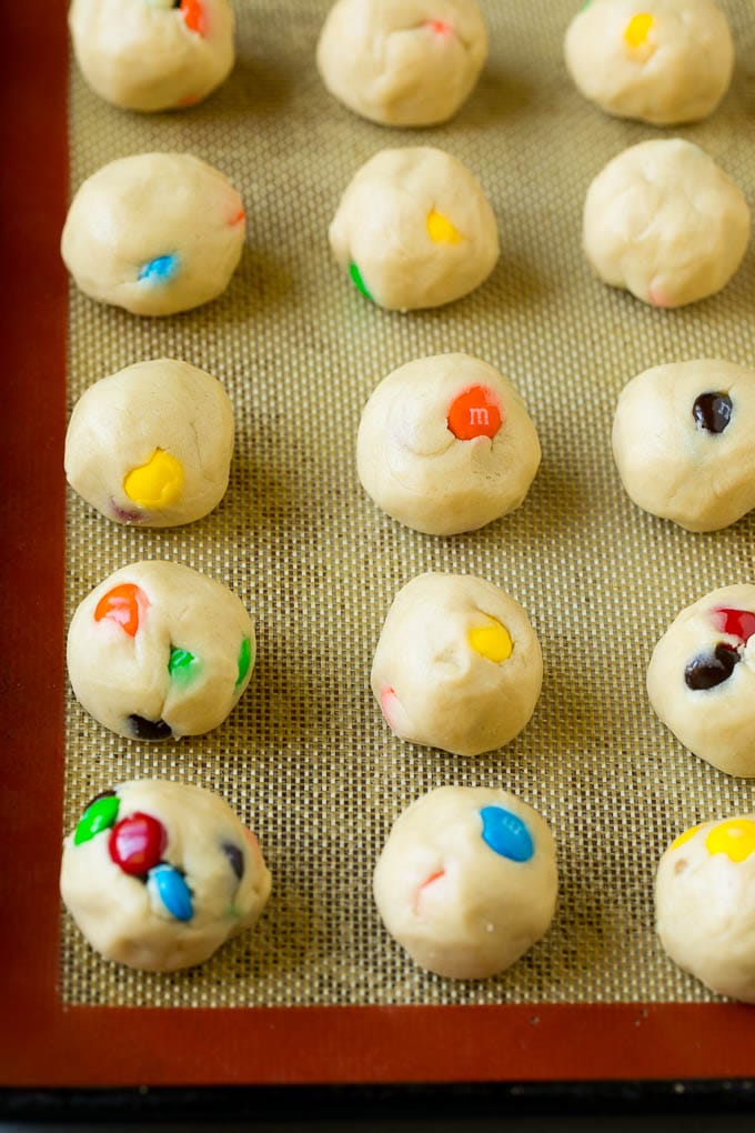 M&M Cookies Recipe #cookies #chocolate #baking #dessert #sweets #ezlod Balls of cookie dough on a baking sheet.