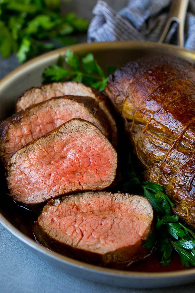 Beef Tenderloin with Garlic Butter #beef #steak #dinner #ezlod A sliced beef tenderloin recipe in a pan, garnished with fresh parsley.