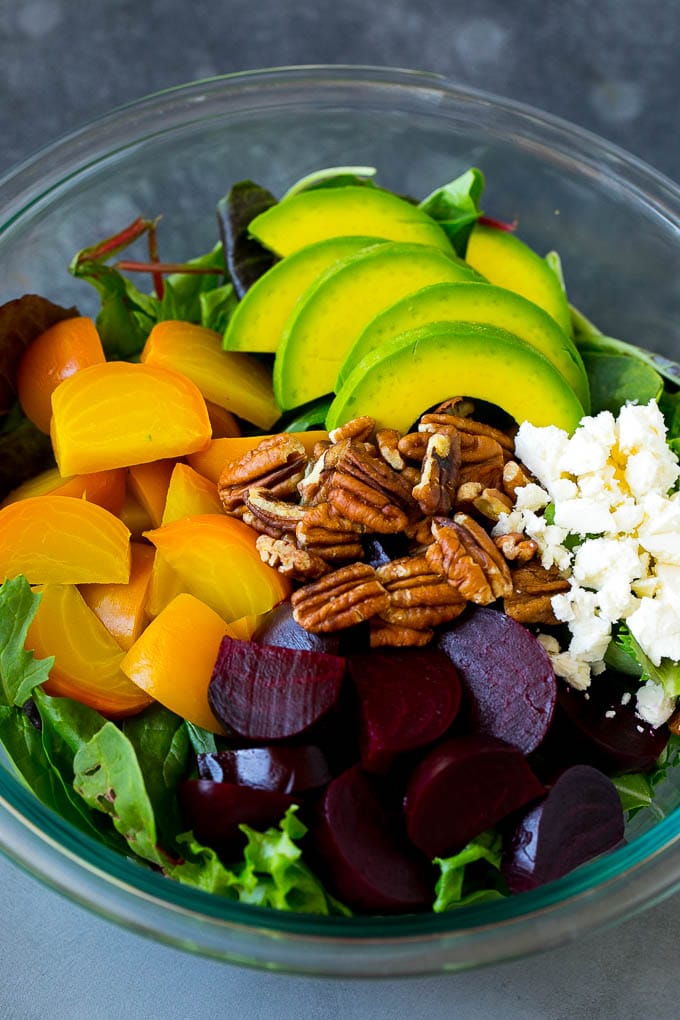 Beet Salad Recipe #beets #avocado #feta #salad #dinner #ezlod Red and yellow beets, salad greens, feta cheese, avocado and pecans in a bowl.