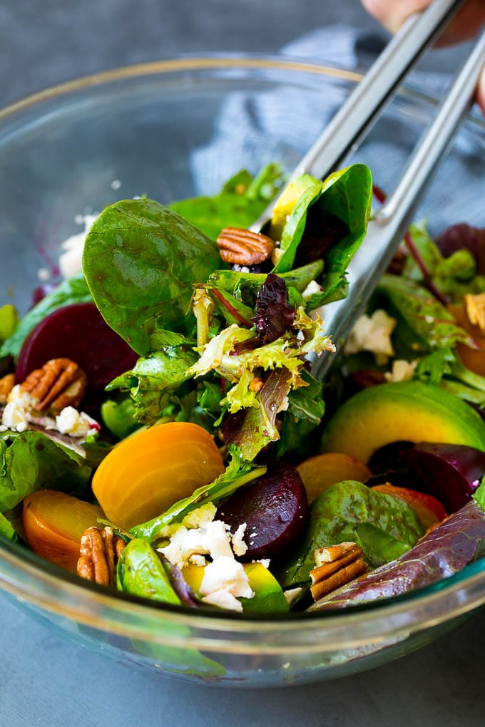 Beet Salad Recipe #beets #avocado #feta #salad #dinner #ezlod Tongs serving a portion of beet salad tossed in balsamic dressing.