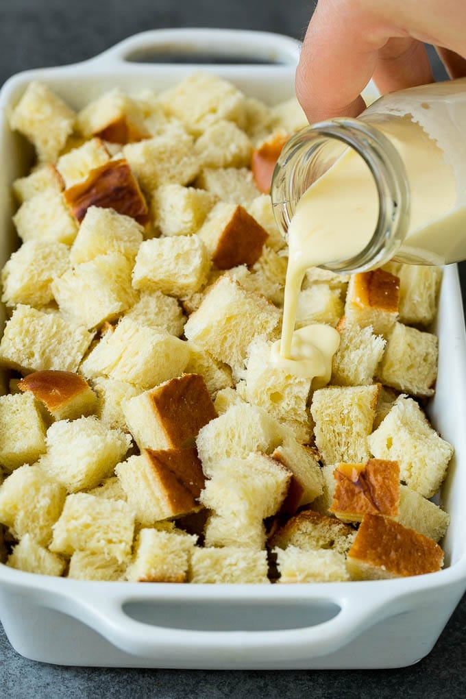 French Toast Casserole Recipe | French Toast Bake #frenchtoast #casserole #breakfast #brunch #ezlod #bread A mixture of milk and eggs being poured over cubes of bread.