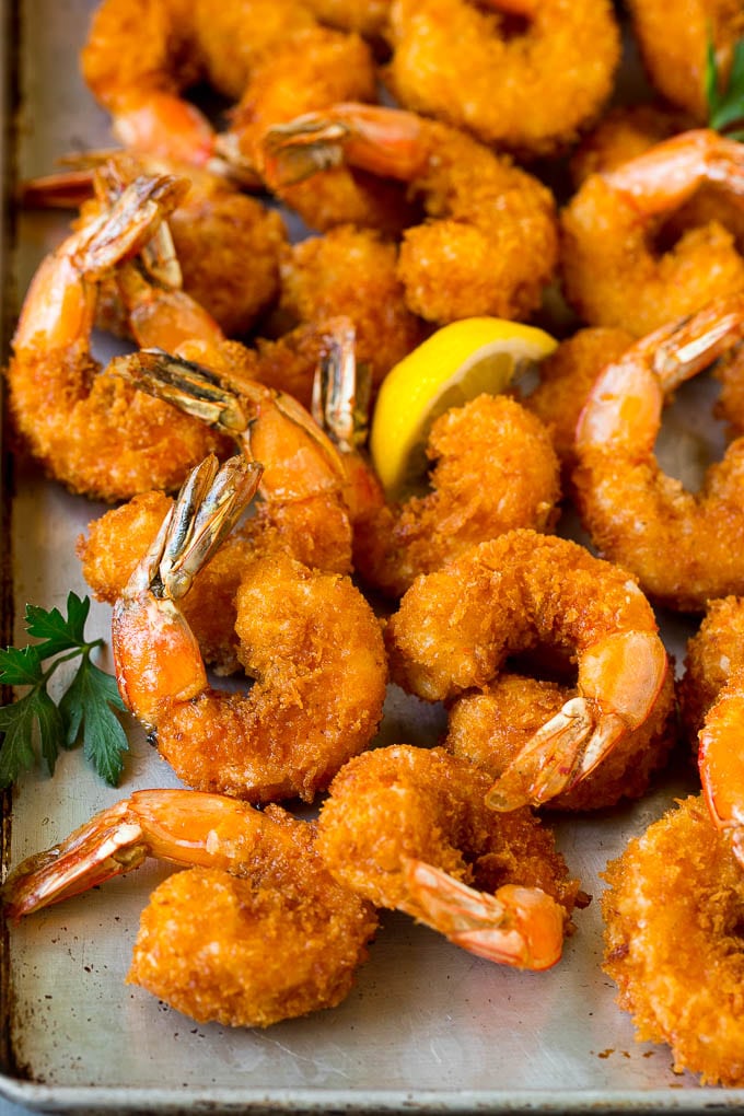 Fried Shrimp Recipe #shrimp #seafood #dinner #appetizer #ezlod Fried shrimp on a sheet pan garnished with parsley and lemon.