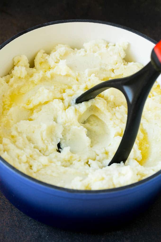 Garlic Mashed Potatoes Recipe #garlic #potatoes #mashedpotatoes #sidedish #dinner #thanksgiving #ezlod A potato masher smashing diced cooked potatoes.