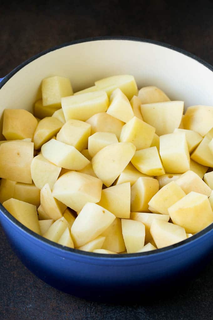 Garlic Mashed Potatoes Recipe #garlic #potatoes #mashedpotatoes #sidedish #dinner #thanksgiving #ezlod Diced potatoes in a large blue pot.