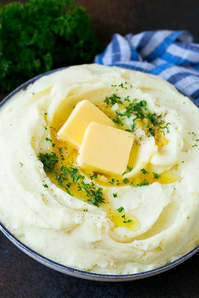 Garlic Mashed Potatoes Recipe #garlic #potatoes #mashedpotatoes #sidedish #dinner #thanksgiving #ezlod Garlic mashed potatoes topped with pats of butter and parsley.