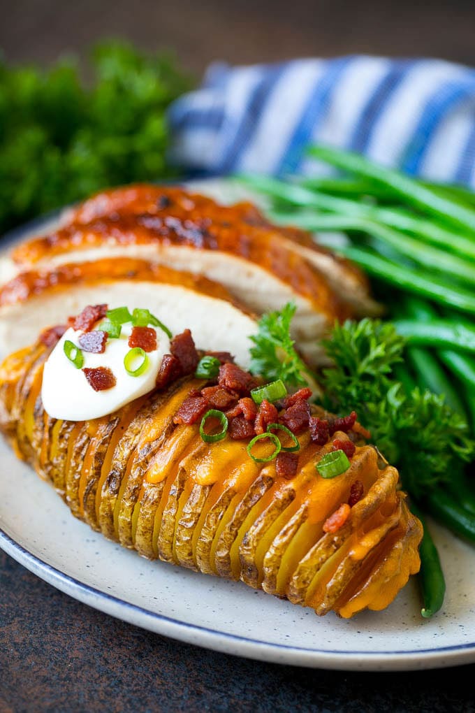 Hasselback Potatoes Recipe #potatoes #bacon #sidedish #cheese #dinner #ezlod Hasselback potatoes on a plate, served with turkey and green beans.