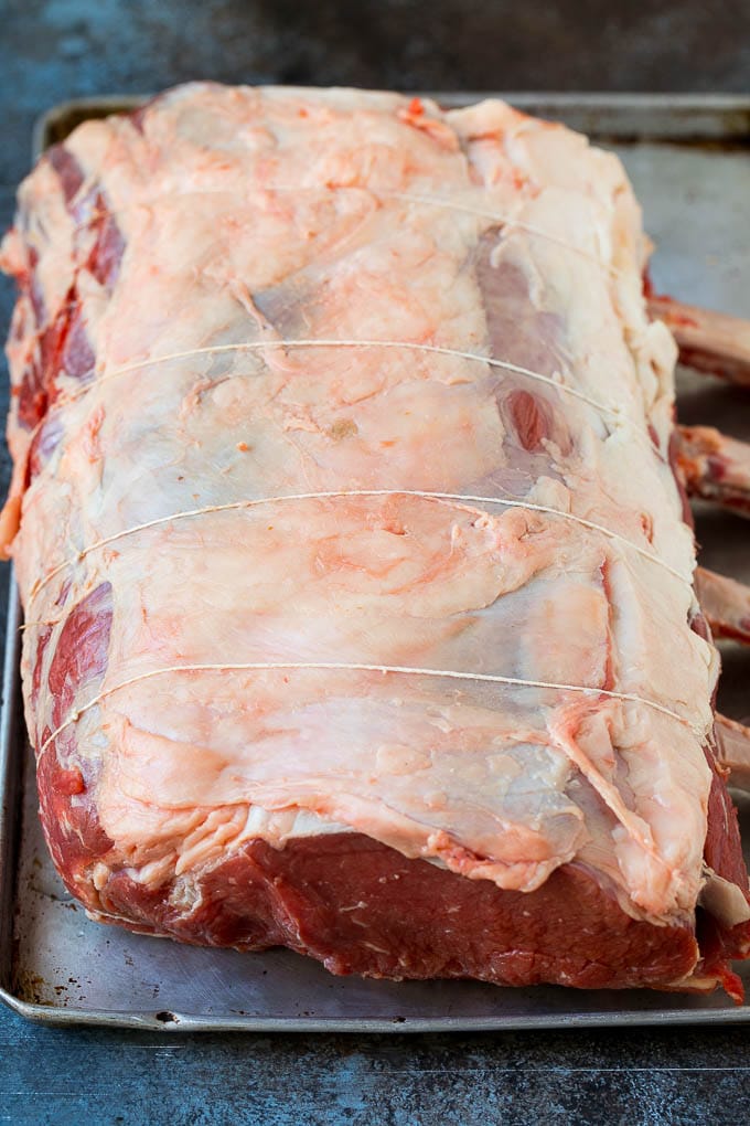 Prime Rib Recipe #primerib #beef #roast #dinner #thanksgiving #christmas #keto #lowcarb #ezlod A tied standing rib roast on a sheet pan.
