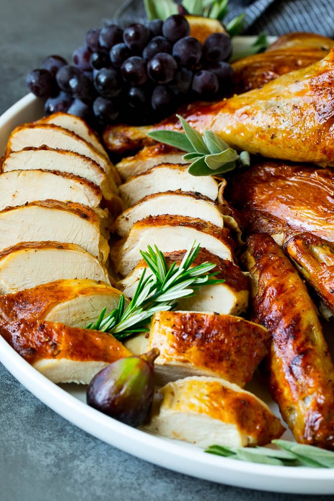 Spatchcock Turkey | Roasted Turkey | Thanksgiving Turkey #turkey #thanksgiving #dinner #fall #christmas #ezlod Sliced spatchcock turkey on a serving platter garnished with herbs.