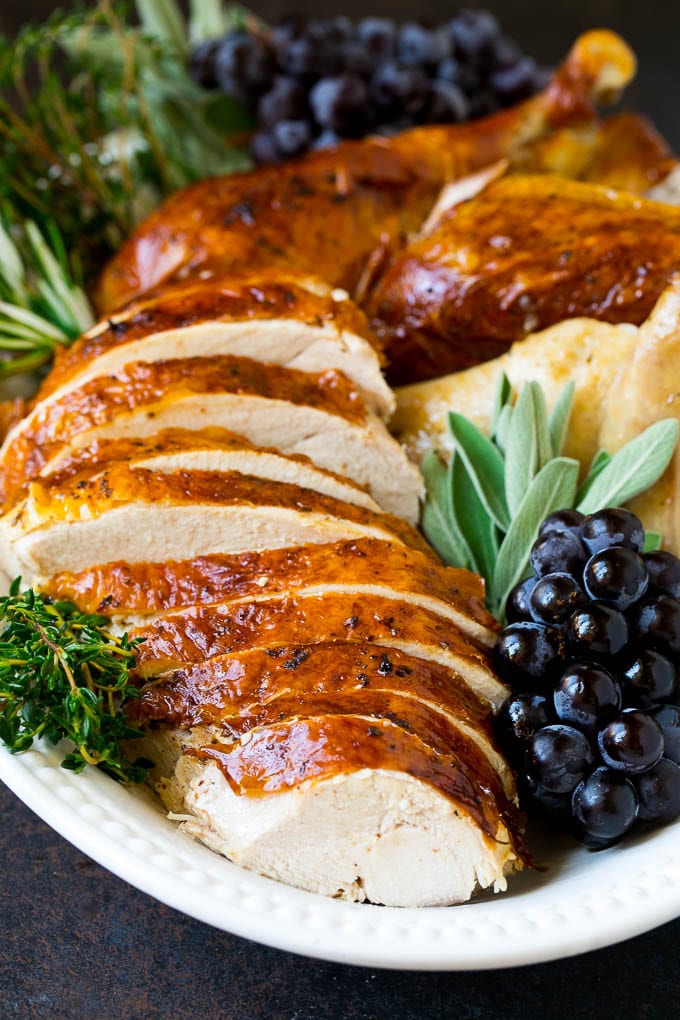 Thanksgiving Turkey Recipe | Roasted Turkey #turkey #thanksgiving #fall #dinner #ezlod Sliced Thanksgiving turkey on a serving platter with fresh herbs.