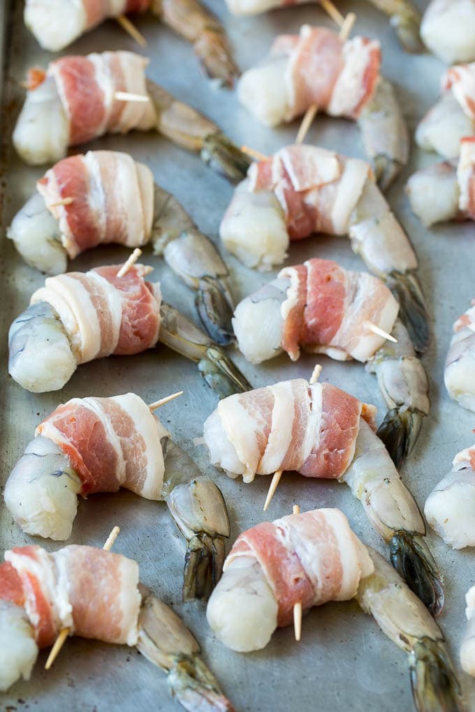 Bacon Wrapped Shrimp Recipe | Bacon Shrimp #shrimp #bacon #appetizer #dinner #ezlod #seafood Raw seafood on a sheet pan wrapped in pork.