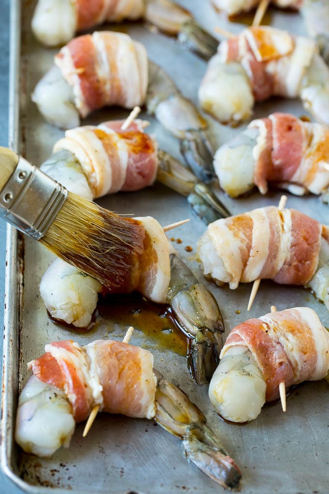 Bacon Wrapped Shrimp Recipe | Bacon Shrimp #shrimp #bacon #appetizer #dinner #ezlod #seafood A basting brush applying sauce to shrimp.