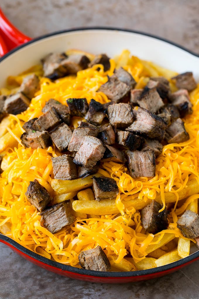 Carne Asada Fries Recipe | Steak Fries #fries #frenchfries #steak #salsa #avocado #cheese #dinner #appetizer #ezlod French fries topped with shredded cheese and diced steak.