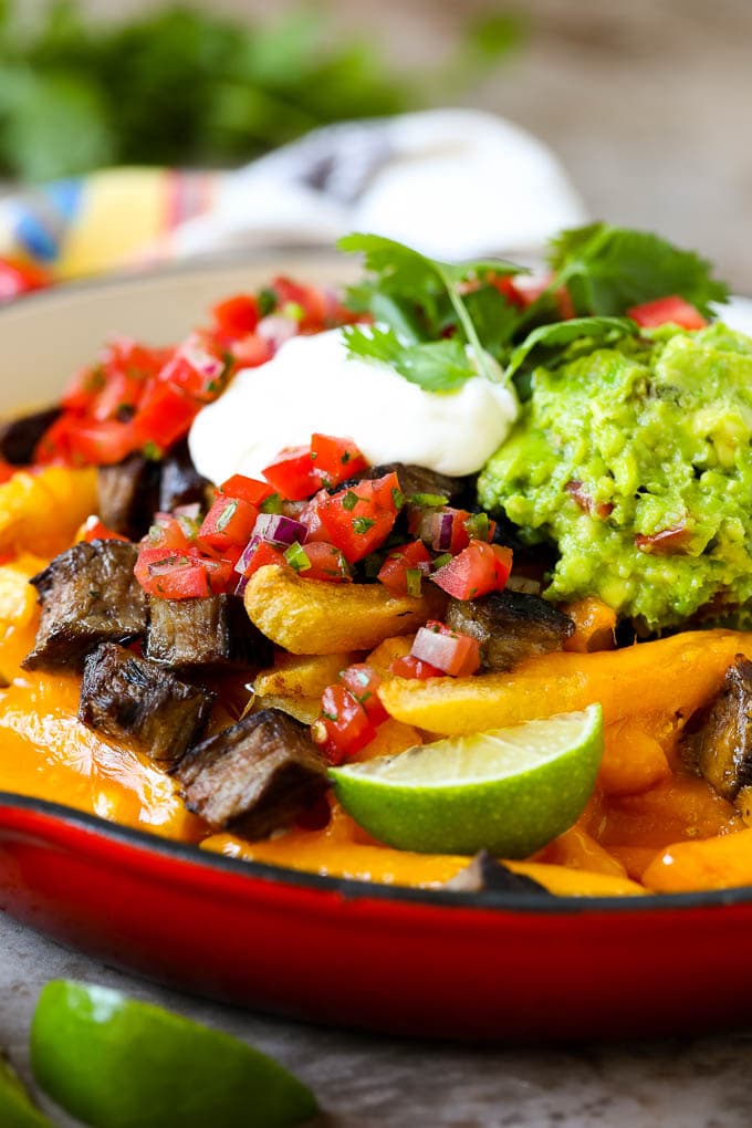 Carne Asada Fries Recipe | Steak Fries #fries #frenchfries #steak #salsa #avocado #cheese #dinner #appetizer #ezlod Carne asada fries in a skillet topped with sour cream, pico de gallo and steak.