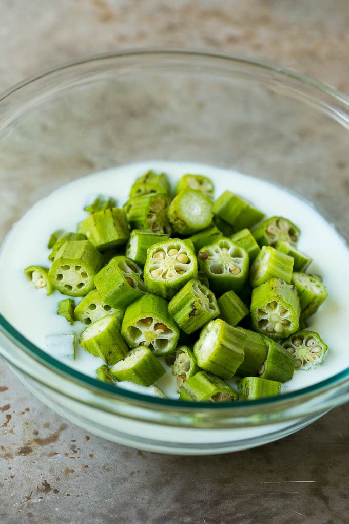 Fried Okra Recipe #okra #appetizer #sidedish #ezlod Sliced okra in a bowl of buttermilk.