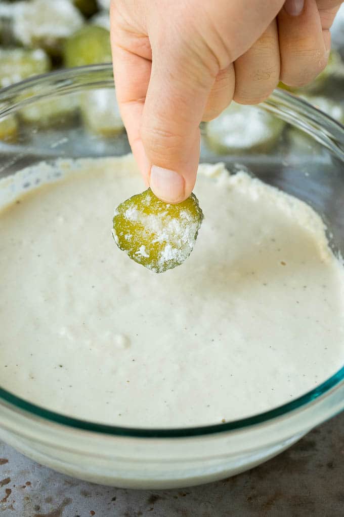 Fried Pickles Recipe #pickles #appetizer #snack #ezlod A slice being dipped into a bowl of beer batter.