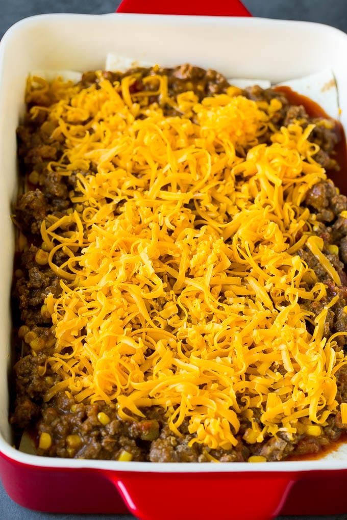 Mexican Lasagna Recipe | Mexican Casserole #mexican #lasagna #groundbeef #beans #dinner #cheese #ezlod Layers of tortillas, ground beef and shredded cheese in a baking dish.