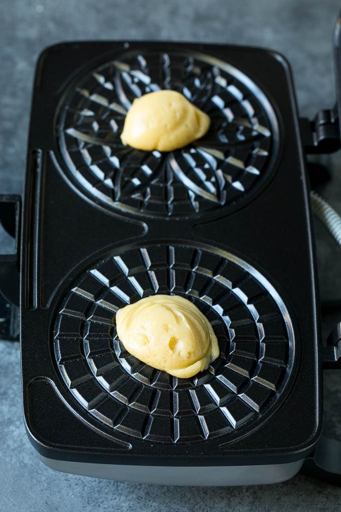 Pizzelle Cookies Recipe #cookies #baking #dessert #christmas #ezlod Dollops of dough in a cookie iron.