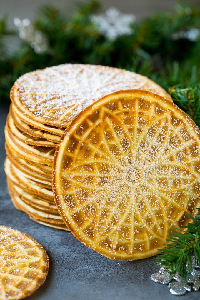 Pizzelle Cookies Recipe #cookies #baking #dessert #christmas #ezlod A stack of pizzelle cookies dusted with powdered sugar.